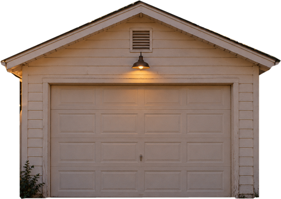 A small beige garage at dusk with a warm lamp glowing above the door